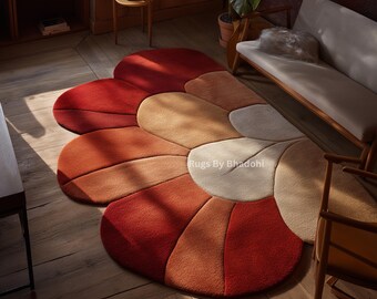 May include: A large, flower-shaped rug with a gradient of warm colors, including red, orange, and beige. The rug is placed on a wooden floor, and the design resembles a stylized flower. The rug is a decorative element for a living room.