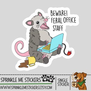 May include: A sticker featuring a cartoon opossum with an open mouth, using a blue laptop. The text reads "BEWARE! FERAL OFFICE STAFF." A yellow mug spills coffee. The sticker has a gray background.