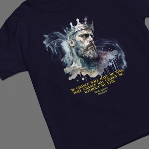 Peut inclure: T-shirt bleu marine avec une illustration à l'aquarelle d'un homme barbu couronné. Le design comprend une citation de Macbeth de Shakespeare : "If chance will have me king..." Un vêtement sur le thème littéraire.