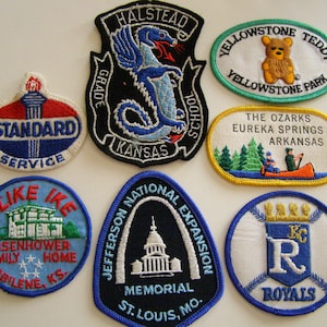 Puede incluir: Una colección de parches bordados vintage con varios diseños y texto. Los parches incluyen un logotipo de Standard Service, un dragón de la escuela Halstead, un oso de peluche de Yellowstone y un parche "I Like Ike".