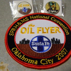 Könnte beinhalten: Sammlung von Erinnerungsstücken mit den Aufschriften "OIL FLYER" und "Santa Fe". Enthält einen großen gestickten Aufnäher mit "SFRH&MS National Convention Oklahoma City 2007" und zwei Anstecknadeln, eine davon mit "El Capitan".