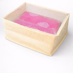 May include: A beige woven storage box with a clear plastic lid, containing a pink item with a white floral design. The box is rectangular and suitable for organizing and storing various household items. The dimensions are in centimeters.