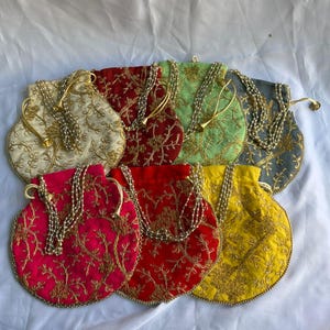 Könnte beinhalten: Eine Sammlung von acht bestickten Beuteln mit Kordelzug in verschiedenen Farben, darunter Creme, Rot, Grün, Grau, Rosa und Gelb. Jeder Beutel hat goldfarbene Stickereien und einen Perlenriemen.