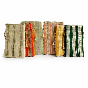 Puede incluir: Colección de seis pequeños bolsos con cordón en varios colores, incluyendo crema, naranja, verde, rosa y amarillo. Cada bolso presenta rayas verticales doradas y ribetes dorados. Los bolsos tienen cordones y borlas doradas.