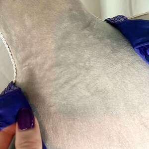 May include: Close-up of a blue garment with sequin and beaded details. The garment has a soft, velvety texture and is adorned with small, round sequins. The straps are embellished with sequins and beads.