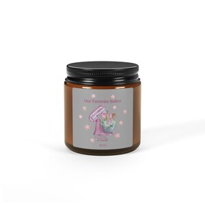 May include: A brown jar with a black lid featuring a label with the text "Our Favorite Baker". The label has a pink stand mixer graphic, flowers, and the name "Tillie" with the year 2025.