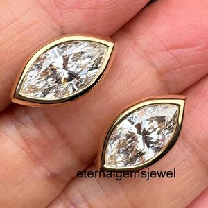 May include: Two marquise-cut clear gemstones set in polished yellow gold bezels. Each stone features a pointed oval shape with multiple facets that reflect light. The text "eternalgemsjewel" is visible in black lettering near the bottom center.