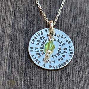 May include: Silver necklace with a round pendant that reads "They've been through a storm. When you've been through a storm, life is like a rainbow. You're a friend." The pendant has a green crystal charm.