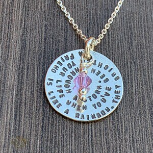 May include: Silver necklace with a round pendant that reads "They've given you a rainbow. When a storm is over, you've been through a bright new horizon. Life is your friend.  You are enough." The pendant has a small pink crystal charm.