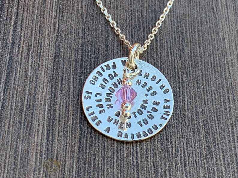 May include: Silver necklace with a round pendant that reads "They've given you a rainbow. When a storm is over, you've been through a bright new horizon. Life is your friend.  You are enough." The pendant has a small pink crystal charm.