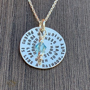 May include: A silver necklace with a round pendant that reads "A friend is like a rainbow. They've been through your life, enough to know when a storm is bright."