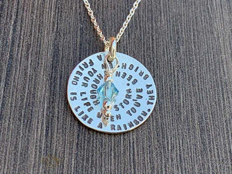 May include: A silver necklace with a round pendant that reads "A friend is like a rainbow. They've been through your life, enough to know when a storm is bright."