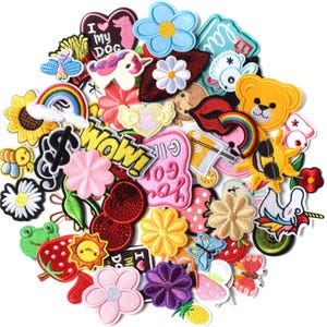 May include: A collection of embroidered patches in various shapes and colors. Designs include flowers, hearts, rainbows, a unicorn, a teddy bear, and text that says "WOW!" and "I MY DOG". These patches are suitable for decorating clothing and accessories.