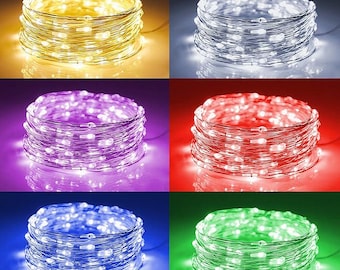 May include: A collection of six spools of LED string lights in various colors. The colors include warm white, cool white, purple, red, blue, and green. Each spool is tightly wound and illuminated, showcasing the different light colors.