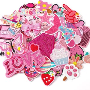 May include: A collection of pink embroidered patches in various shapes and designs. Includes a butterfly, a diamond, a cupcake, a mermaid tail, a roller skate, and the word "LOVE".