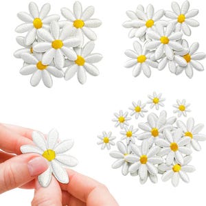 Puede incluir: Parches de flores de margarita blancas bordadas con centros amarillos. La imagen muestra varios grupos de parches de margarita, algunos en grupos y uno sostenido por una mano. Ideal para añadir un toque floral a la ropa o accesorios.