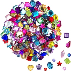 Peut inclure: Un assortiment de pierres précieuses artisanales colorées de différentes formes et tailles. Les pierres précieuses comprennent des cœurs, des étoiles, des fleurs et des formes géométriques dans des tons de rose, de bleu, de vert, de rouge, de jaune et de violet.