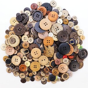 May include: A collection of various buttons in shades of brown, beige, and black. The buttons vary in size and material, including wood and plastic, with two or four holes. Some buttons have text or designs, such as the word "Mickey".