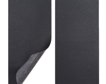 May include: Two sheets of black faux leather material. One sheet has a corner peeled back, revealing a gray backing. The surface of the material has a textured, pebbled appearance. The sheets are rectangular and set against a white background.