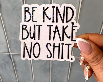 Puede incluir: Una pegatina troquelada con un fondo holográfico de estrellas que contiene el texto negro BE KIND BUT TAKE NO SHIT. La pegatina tiene un borde blanco y un acabado brillante, mostrando una superficie reflectante que capta la luz.