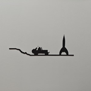 Peut inclure: Décoration murale en métal noir représentant une silhouette de jeep roulant sur une route vers une fusée. L'œuvre d'art est de conception minimaliste, avec des lignes épurées et une finition mate. La jeep est détaillée avec des passagers.