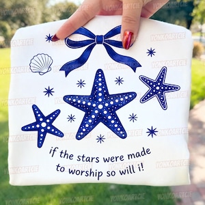 Peut inclure: Tissu blanc avec un motif de nœud bleu, d'étoiles de mer et de coquillage. Le texte "if the stars were made to worship so will i!" est inclus. Les étoiles de mer ont des motifs de points blancs.