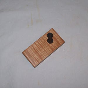 Könnte beinhalten: Eine kleine Holzkiste mit zwei schwarzen Kreisen, die aus der Oberseite ausgeschnitten sind.