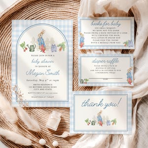 Könnte beinhalten: Babyparty-Einladungsset mit blauem Vichy-Muster. Die Einladung zeigt eine Aquarellillustration eines Kaninchens in einem blauen Mantel und roten Stiefeln. Enthält Karten für Bücher, Windel-Tombola und Dankeskarten.