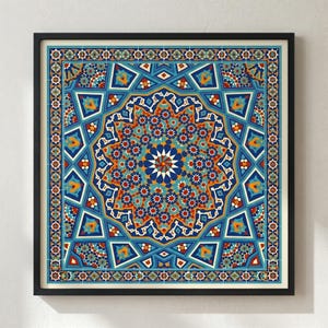 May include: A framed print featuring a detailed geometric design in shades of blue, orange, and white. The artwork has a central starburst pattern surrounded by intricate repeating shapes and a decorative border. The frame is black.