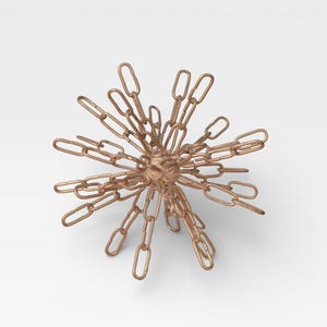 May include: A bronze-colored decorative object resembling a burst of chains. The chains radiate outwards from a central sphere, creating a starburst design. The links are oval-shaped and have a metallic finish.