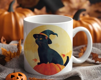 May include: White ceramic mug featuring a black cat wearing a witch hat, sitting on a pumpkin. The design is set against a yellow backdrop with autumn leaves. A small carved pumpkin sits in front of the mug.