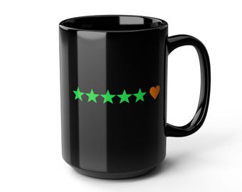May include: A black ceramic mug featuring a design of five green stars and a small orange heart. The mug has a large handle and a glossy finish. This mug is suitable for hot or cold beverages.