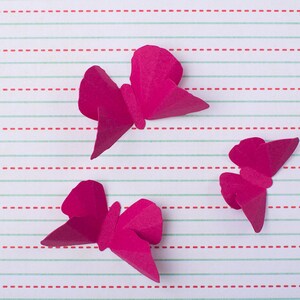 May include: Three pink paper butterflies on a white and red striped background.