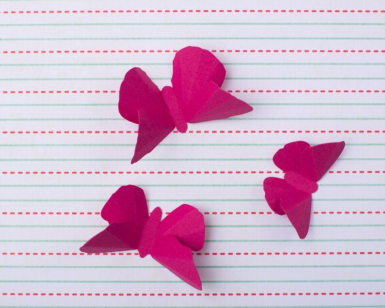 May include: Three pink paper butterflies on a white and red striped background.
