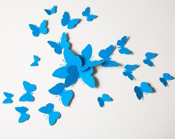 May include: A white background with a cluster of blue paper butterflies arranged in a starburst pattern. The butterflies are all the same size and shape, and they are all facing the same direction.