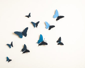 May include: A white wall with multiple blue and black paper butterflies attached to it. The butterflies are in various sizes and positions.