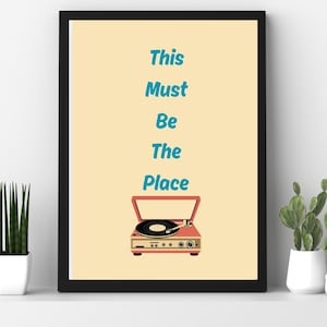 Può includere: Stampa artistica incorniciata con un'illustrazione di giradischi retrò in rosso e crema, con il testo turchese "This Must Be The Place". L'opera d'arte è su sfondo crema.