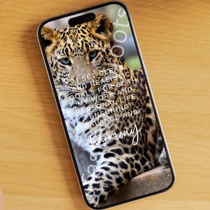 May include: A smartphone displaying a high-resolution image of a leopard with its fur pattern clearly visible. Overlaid on the leopard image is white text that reads: I SET CLEAR AND REALISTIC GOALS FOR BOTH MY WORK AND PERSONAL LIFE, ENSURING BALANCE AND harmony.