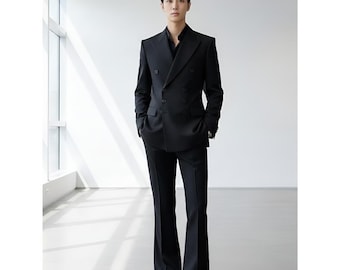 May include: A man in a black double-breasted suit with flared pants and a black shirt. The suit has a classic design. The image includes the letters "ZB" in the upper right and lower left corners.