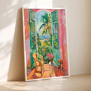 May include: Framed art print showing a balcony scene with green shutters. The painting features a wicker chair, small table, and flowers. The view includes palm trees, the sea, and buildings, with pink and orange walls.