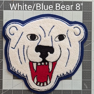 May include: White and blue embroidered bear patch, 8 inches in size. The bear has a white face with black eyes, a black nose, and a red mouth. The patch is outlined in blue and features the text "White/Blue Bear 8".