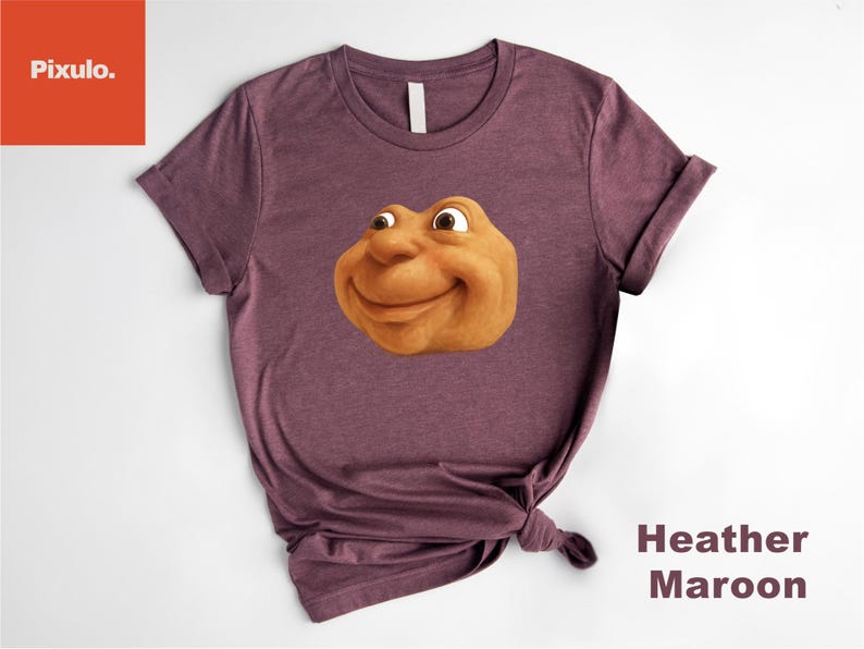 May include: Heather maroon t-shirt featuring a smiling, cartoonish face with brown skin and large eyes. The shirt is knotted at the bottom. The words "Heather Maroon" are printed in a vertical format on the right side.