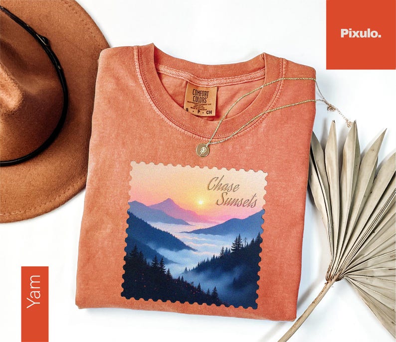 May include: A coral-colored t-shirt with a landscape graphic featuring mountains, trees, and a sunset, with the text "Chase Sunsets." A gold necklace and a brown hat are also visible.