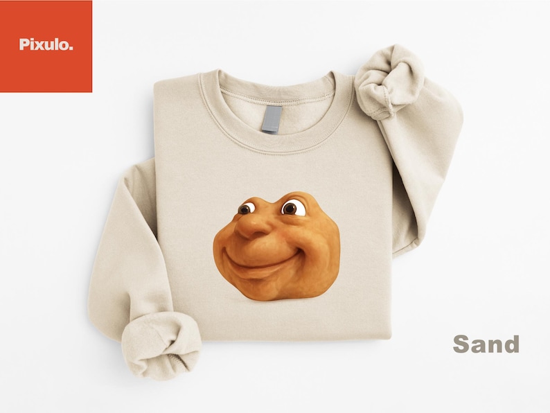 May include: Sand-colored sweatshirt featuring a smiling, cartoonish face. The face is a warm, earthy tone with large eyes and a friendly expression. The word "Sand" is printed in a dark color on the bottom right.