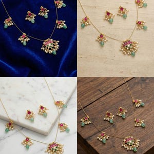 May include: A gold-toned necklace and earring set. The necklace features a central pendant with a pink and green floral design, surrounded by small white pearls and green and red gemstones. The earrings mirror the design. The set is displayed on a blue velvet surface.
