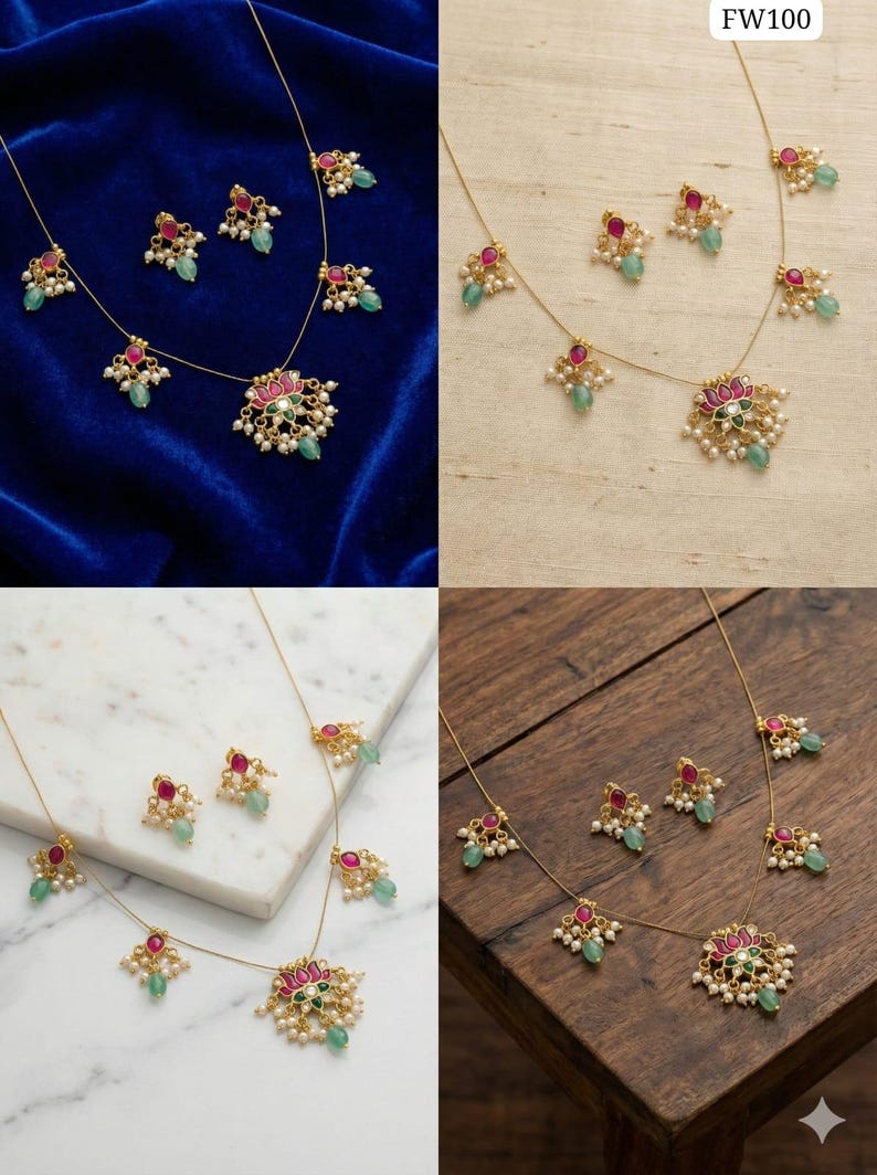 May include: A gold-toned necklace and earring set. The necklace features a central pendant with a pink and green floral design, surrounded by small white pearls and green and red gemstones. The earrings mirror the design. The set is displayed on a blue velvet surface.