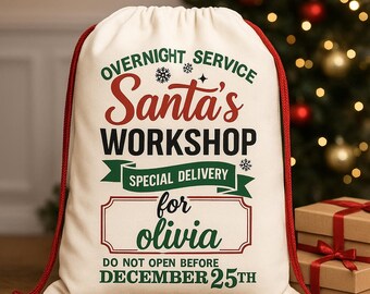Pode incluir: Uma sacola de presente creme da Oficina do Papai Noel com cordão vermelho. O texto inclui "Overnight Service", "Santa's Workshop", "Special Delivery" e "for Olivia". A parte inferior diz "Do Not Open Before December 25th".
