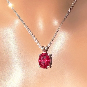 May include: A silver chain necklace with a red oval pendant.