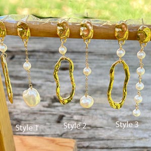 Peut inclure: Boucles d'oreilles dorées avec des perles présentées sur un présentoir en bois. Les boucles d'oreilles varient en style, avec des formes organiques et des perles pendantes. L'image est bien éclairée, mettant en valeur les détails des bijoux. Style 1, Style 2 et Style 3 sont étiquetés.