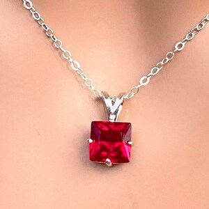 May include: A silver chain necklace with a square-shaped red ruby pendant. The pendant is 8 mm in size. 8 mm Ruby Square Style